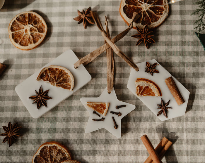 Aroma Quartz scented wax tree decorations in rectangle and star shapes on a gingham cloth with dried orange and star anise