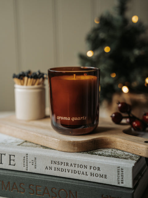Winter Orchards candle in an amber glass jar on a wicker tray with dried orange slices and matches