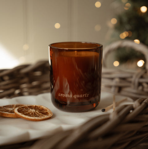Real Fir Trees candle in an amber glass jar on a wicker tray with dried orange slices and matches