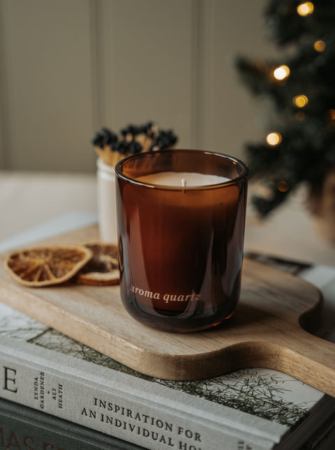 Winter Orchards refillable candle on a wooden board with a dried orange slice and a Christmas tree