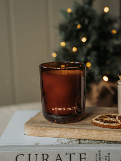 Real Fir Trees refillable candle on a wooden board with dried orange slices and a Christmas tree behind