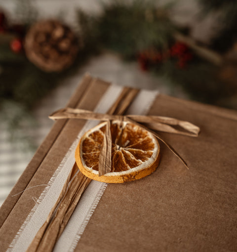 Kraft wrapped gift box tied with raffia and a dried orange slice, close up