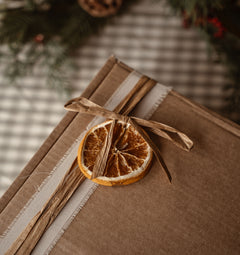 Gift box wrapped in kraft paper with raffia and a dried orange slice