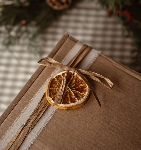 Gift box wrapped in kraft paper with raffia and a dried orange slice