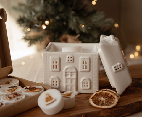 Ceramic house wax melt warmer with the roof lifted off beside a box of winter wax melts
