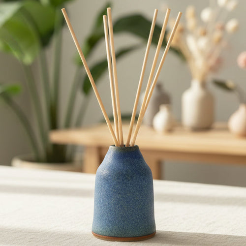 Winter Alpine refillable ceramic diffuser in blue stoneware with reed sticks on a table