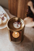 Individual Botanical Wax Melts — melting wax melt in a gold oil burner with decorative elements on a soft surface