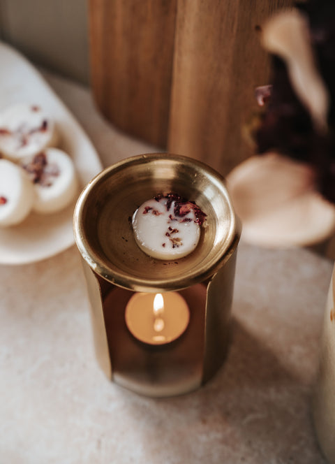 Individual Botanical Wax Melts — melting wax melt in a gold oil burner with decorative elements on a soft surface