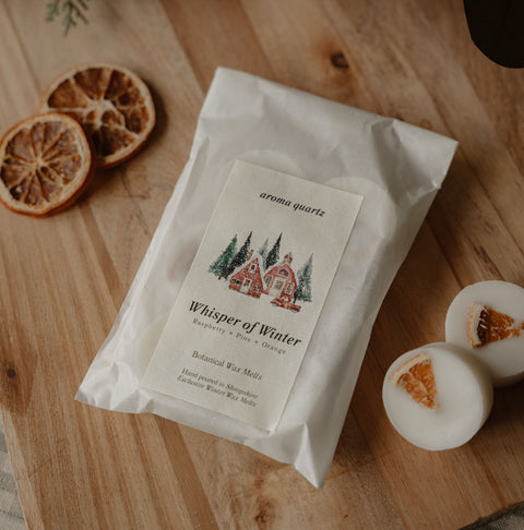 Whisper of Winter wax melt packet with wax melts and dried orange slices on a wooden board