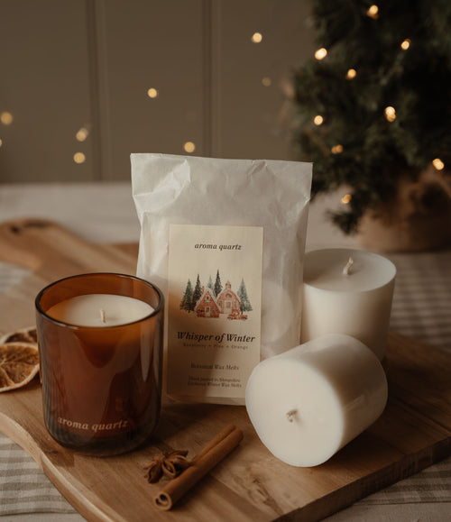 Amber refillable candle, wax refill pods and a Whisper of Winter melt packet on a wooden board