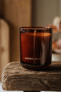 Brown candle in a glass holder labeled 'aroma quartz' on a wooden surface.