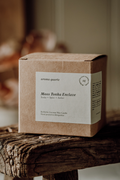 Moss Tonka Enclave candle by Aroma Quartz — kraft paper box packaging on wooden surface