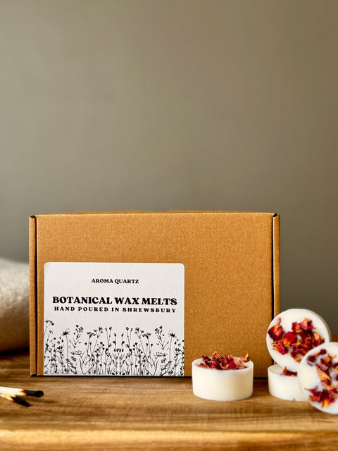 Box of Aroma Quartz Botanical Wax Melts on a wooden surface with a neutral background styled with oil burner melts and match sticks
