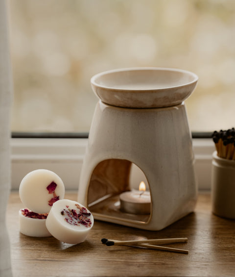 Ceramic oil burner with natural botanical wax melts and matches on a wooden surface