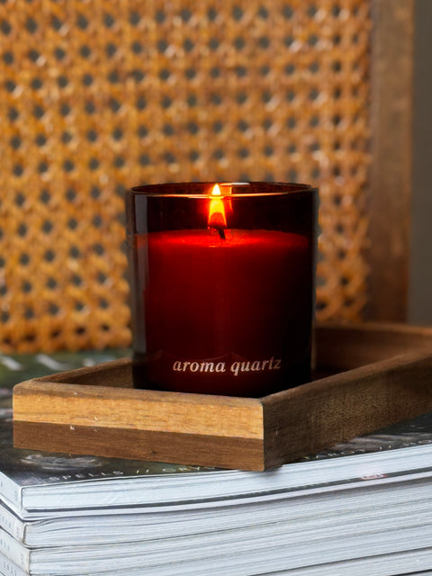 amber refillable candle engraved with 'aroma quariz' on a wooden tray with a textured background