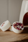 Natural wax botanical wax melts with dried flowers on a wooden surface, with a blurred background