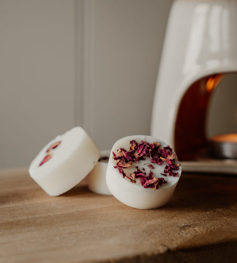 Natural wax botanical wax melts with dried flowers on a wooden surface, with a blurred background